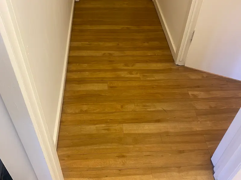 Scuffed, flat wood-look vinyl in a clinic hallway before polishing