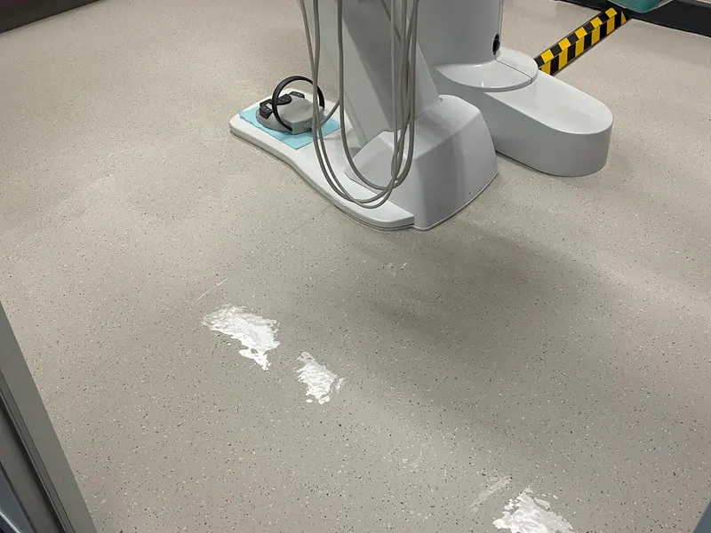 Fresh polish being applied to speckled vinyl around a dental chair
